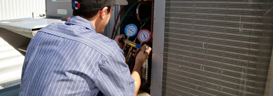HVAC technician servicing a condenser unit in Lantana